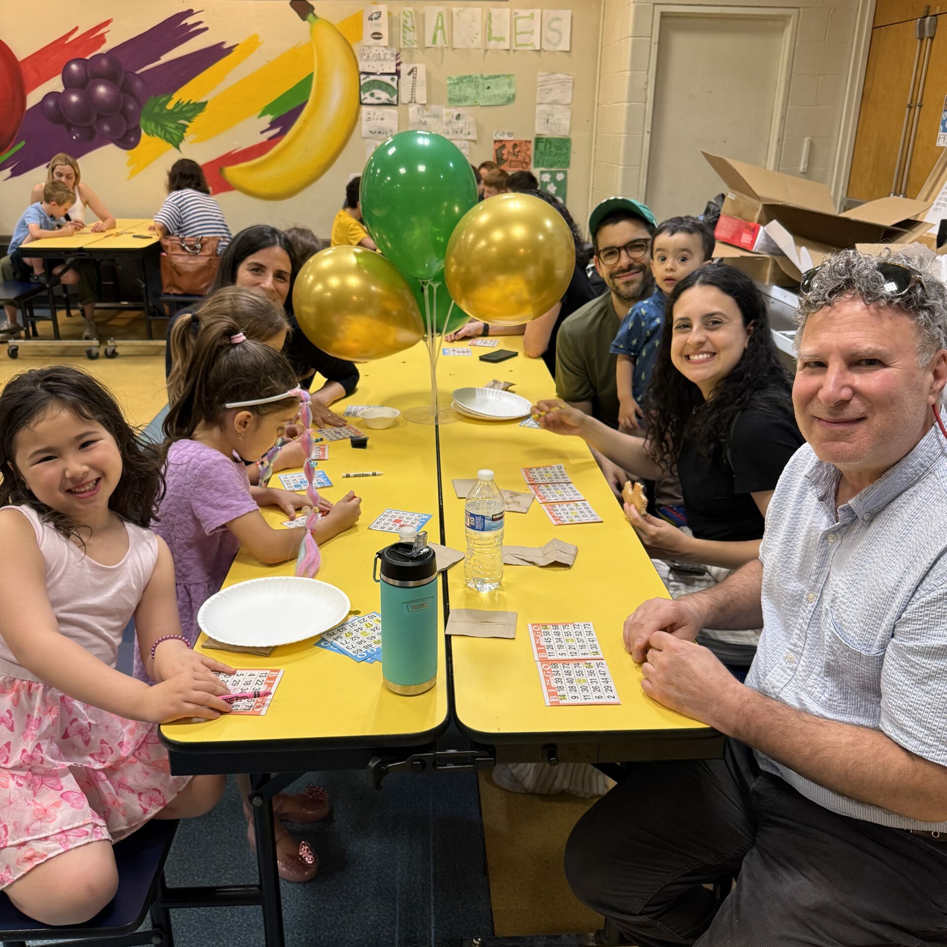 Students and families seated at tables playing bingo together during a school community event at Albert M. Greenfield School in Philadelphia